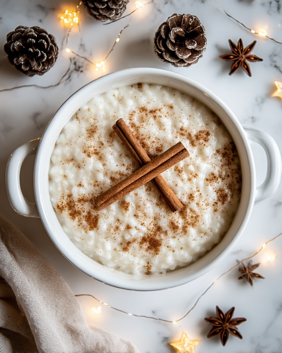 A bowl of creamy rice pudding with a smooth, slightly lumpy white texture fills the white bowl with handles. The pudding is topped with a light dusting of brown cinnamon powder spread evenly, and two whole cinnamon sticks crossed in the center. The bowl sits on a white marbled surface decorated with pine cones, star anise, a light string of warm small yellow lights, and part of a soft beige cloth partially visible in the bottom left corner. The overall scene gives a cozy, warm feeling. photo taken with an iphone --ar 4:5 --v 7