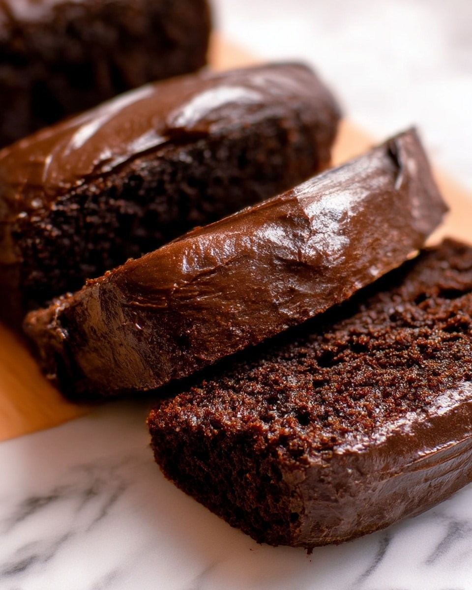 Three thick slices of rich, dark chocolate cake with a smooth, glossy layer of chocolate frosting on top are arranged closely together. The cake looks moist with a dense, slightly crumbly texture, and the frosting has a shiny, creamy finish covering the top surface of each slice. The background is a white marbled texture, adding brightness to the deep brown colors of the cake. photo taken with an iphone --ar 4:5 --v 7