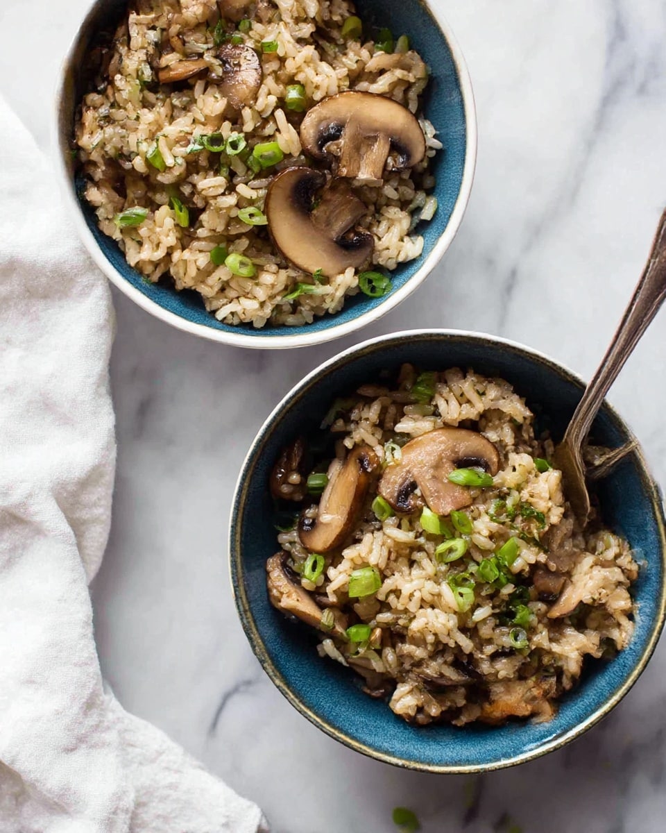 The image shows two white bowls filled with mushroom rice; the bowls have a blue outer glaze and sit on a white marbled surface. The rice is light brown and mixed with medium to large sliced cooked mushrooms, and finely chopped green onions are scattered throughout the dish. The texture of the rice looks soft and slightly glossy, and the mushrooms have a cooked, tender appearance with some browning. A silver fork rests inside one bowl, partially buried in the rice, and a white cloth is placed near the bowls on the surface. Photo taken with an iphone --ar 4:5 --v 7