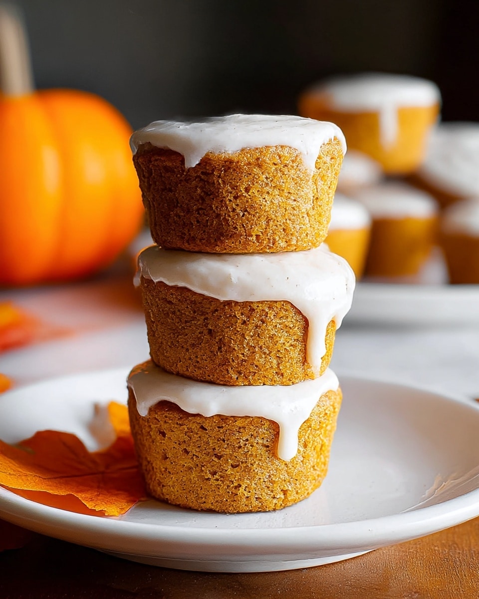 Three pumpkin muffins are stacked on a white plate set on a white marbled surface. Each muffin has a thick layer of creamy white frosting on top, with the top muffin’s frosting slightly dripping over the edge. The muffins are golden brown with a soft, moist texture visible. In the blurry background, more muffins with similar frosting are seen, along with an orange pumpkin and autumn-colored leaves near the plate. The overall look is warm and cozy, perfect for fall. photo taken with an iphone --ar 4:5 --v 7