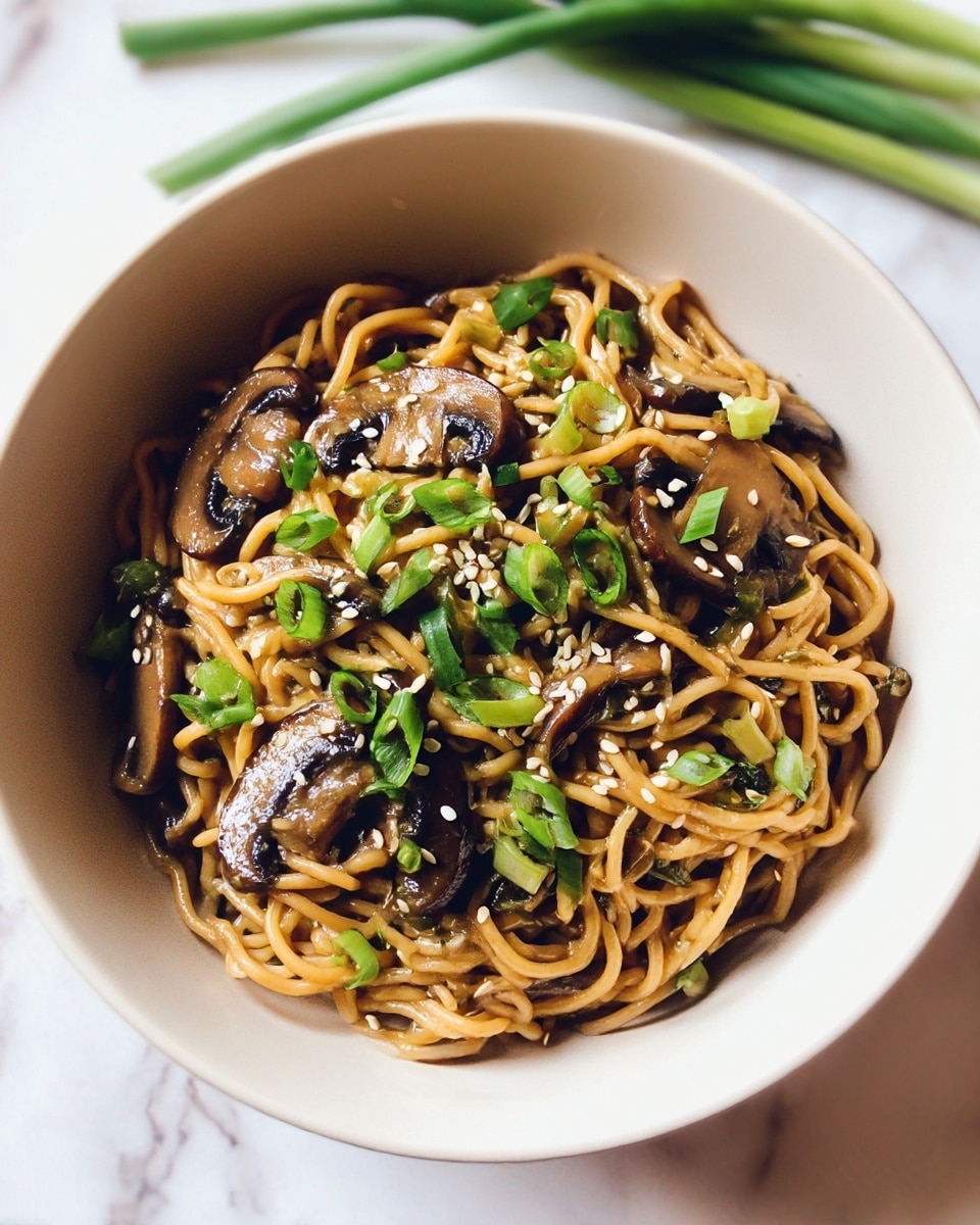 A white bowl filled with a single layer of light brown cooked noodles, mixed with slices of dark brown sautéed mushrooms scattered throughout. Bright green chopped spring onions are sprinkled on top along with small white sesame seeds, adding texture and color contrast. The bowl is set against a white marbled surface with some green onion stalks blurred in the background. photo taken with an iphone --ar 4:5 --v 7