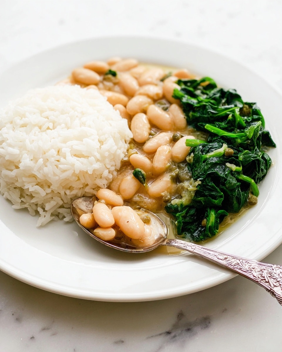 The dish shows three parts on a white plate with a simple edge design, placed on a white marbled surface. On the left, there is a pile of white rice with a fluffy texture, slightly translucent. To the right of the rice, in front, is a creamy bean stew with plump, pale beige beans in a light sauce with small pieces of celery and green capers visible, giving a soft, smooth look. On the far right, there is a portion of cooked dark green spinach with a shiny, slightly wet texture. A silver spoon with a floral pattern on the handle rests on the right side of the plate, partly on the spinach. Photo taken with an iphone --ar 4:5 --v 7