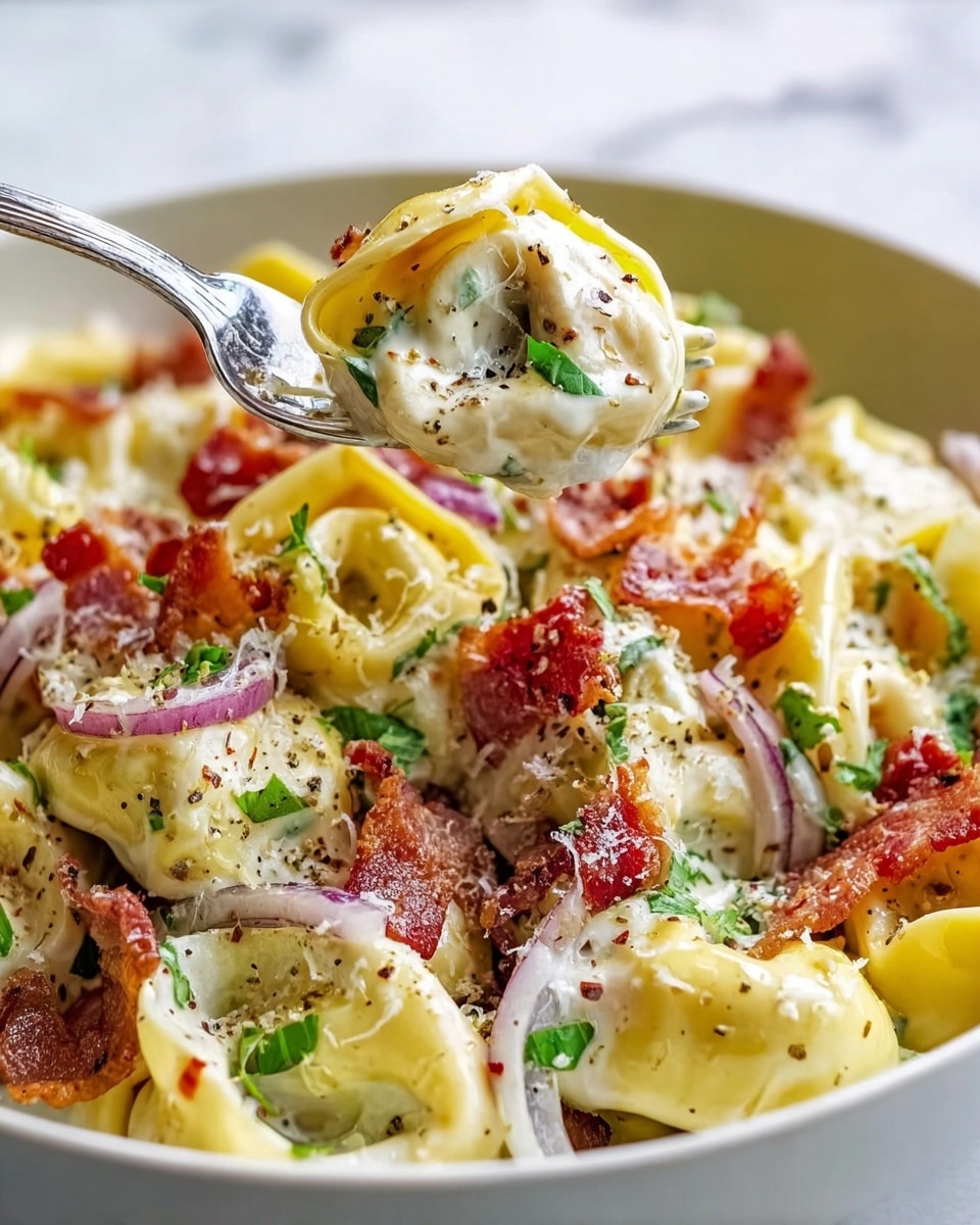 The image shows a close-up of creamy tortellini pasta served in a white bowl on a white marbled surface. The dish has several layers: the first layer is filled tortellini with a smooth, yellowish pasta texture, covered in a thick white cream sauce. Scattered on top are crispy pieces of reddish-brown bacon, thin slices of purple onion, and fresh green herbs sprinkled throughout. The pasta is also dusted with finely grated white cheese and black pepper flakes. A silver fork lifts a piece of tortellini, revealing the creamy inside mixed with bacon bits. Photo taken with an iphone --ar 4:5 --v 7