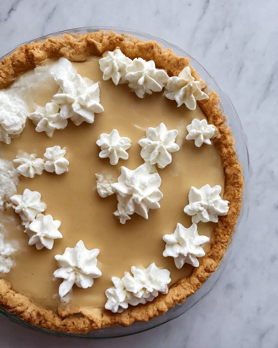 A white plate with a single slice of lemon pie showing three layers: a light golden flaky crust on the bottom, a bright yellow smooth lemon filling in the middle, and a few white whipped cream dollops on top placed near the edge; a shiny honey or syrup glaze is drizzled over the slice and plate around it. In the background, there is another white plate with a similar slice, and two silver forks lie nearby on a white marbled surface. photo taken with an iphone --ar 4:5 --v 7