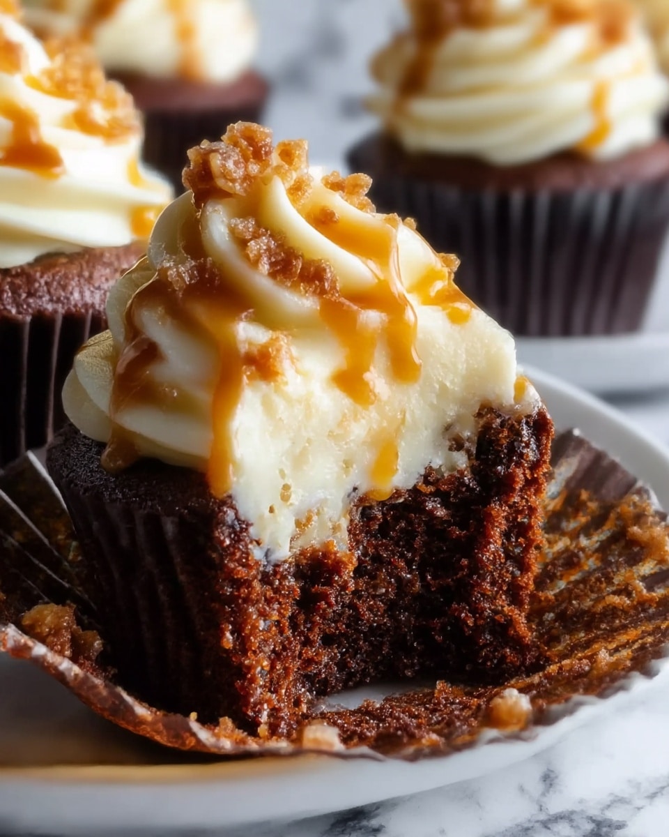 A close-up image shows a chocolate cupcake with two visible layers: a dark, moist chocolate cake base on the bottom and a thick swirl of creamy white frosting on top. The frosting is smooth and fluffy with a wavy texture. A golden caramel sauce is drizzled over the frosting, and small bits of crunchy topping are scattered on it. The cupcake liner is dark brown, and part of the cupcake is bitten off, showing the soft crumb inside. The cupcakes sit on a white plate placed on a white marbled surface. photo taken with an iphone --ar 4:5 --v 7