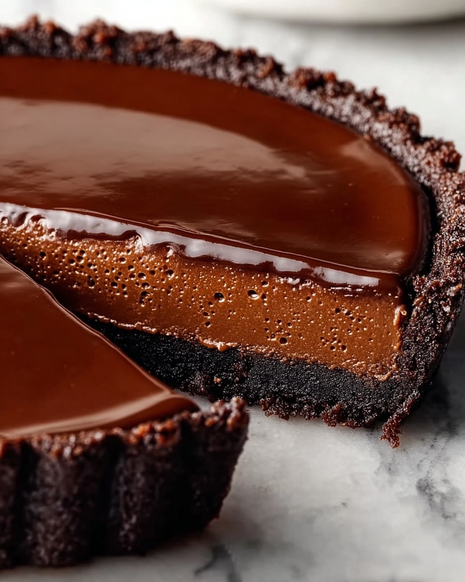 A close-up of a sliced chocolate tart with three distinct layers is shown. The bottom layer is a dark, crumbly chocolate crust with a rough texture. Above it, there is a thick, smooth milk chocolate filling that has a slightly bubbly surface. On top, a shiny, dark chocolate glaze forms a thin, glossy layer. The tart is placed on a white marbled surface. photo taken with an iphone --ar 4:5 --v 7