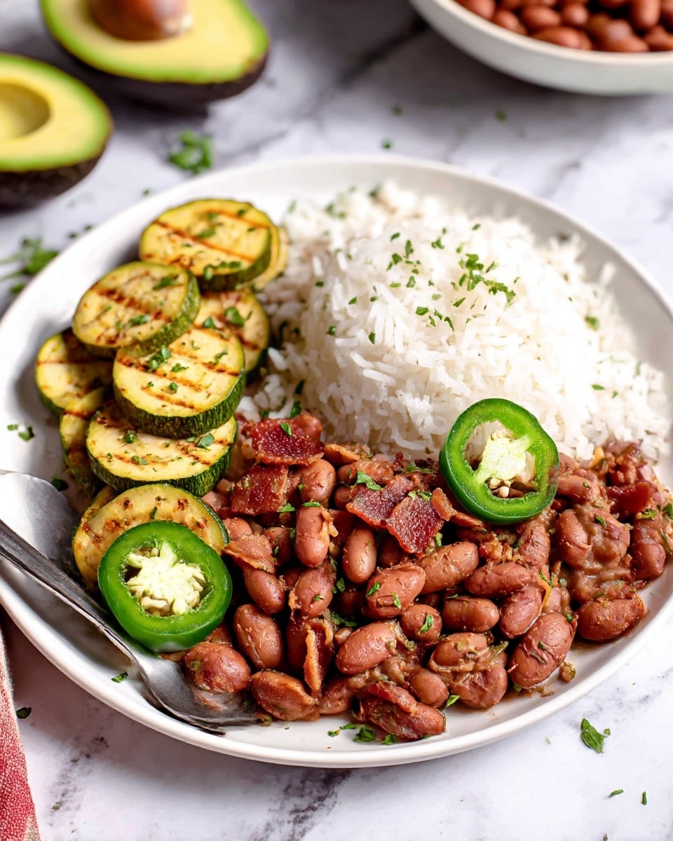 A white bowl filled with cooked pinto beans mixed with small pieces of browned meat and finely chopped herbs, all coated in a slightly thick, reddish-brown sauce. On top are two slices of bright green jalapeño peppers showing their seeds. The beans and meat have a soft, moist texture with some pieces slightly crispy. A silver spoon is placed inside the bowl, partially submerged in the saucy mixture. The bowl sits on a white marbled surface, creating a clean and fresh background. Photo taken with an iphone --ar 4:5 --v 7