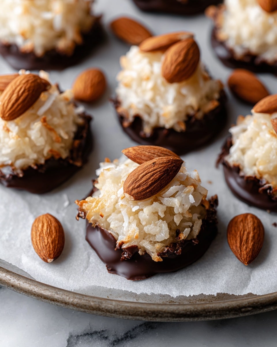 The image shows several coconut macaroons arranged on white parchment paper, each macaroon has a textured, light beige shredded coconut top layer, and a smooth dark chocolate bottom layer with some rough edges, the tops are decorated with one or two whole almonds that have a shiny surface and a warm, brown color; the arrangement is on a round container edge which is partially visible with a dull color, and the background is a white marbled texture photo taken with an iphone --ar 4:5 --v 7