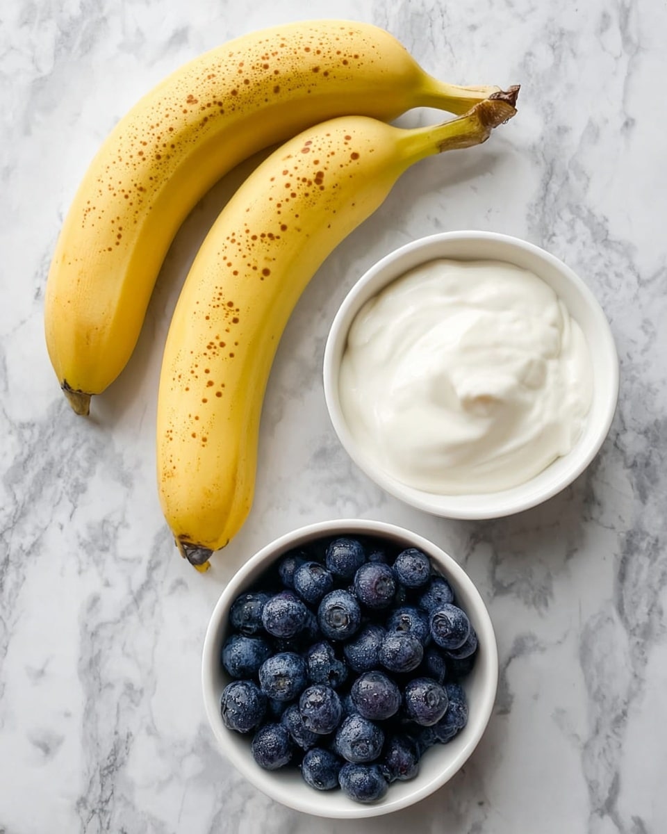 The image shows two yellow bananas with small brown spots placed side by side on a white marbled surface. Below the bananas, there are three small white bowls: one is filled with smooth white yogurt, and the other two are filled with fresh, round, dark blue blueberries. The blueberries in each bowl are plentiful and have a slightly frosted texture. The overall arrangement of the fruit and bowls is neat and clean. photo taken with an iphone --ar 4:5 --v 7