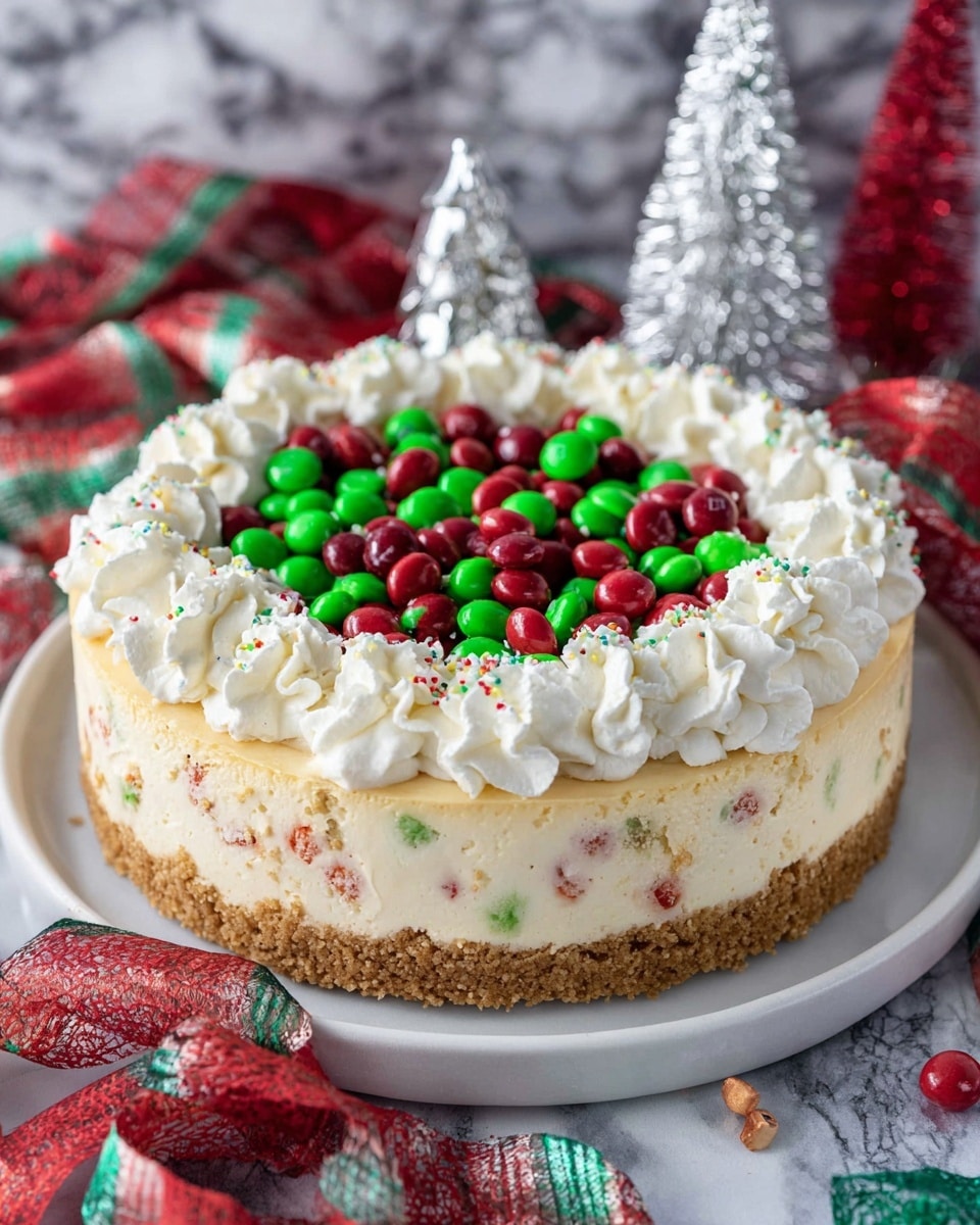 A slice of cheesecake with three main layers sits on a white square plate on a white marbled surface. The base layer is a crumbly light brown crust. The thick middle layer is creamy and pale yellow with red and green speckles mixed throughout, giving a festive look. On top, there is a smooth pale beige layer covered partially by red and green candy pieces. A generous amount of white whipped cream is piled on one side of the slice. In the blurry background, the rest of the cheesecake with similar decorations can be seen. Photo taken with an iphone --ar 4:5 --v 7