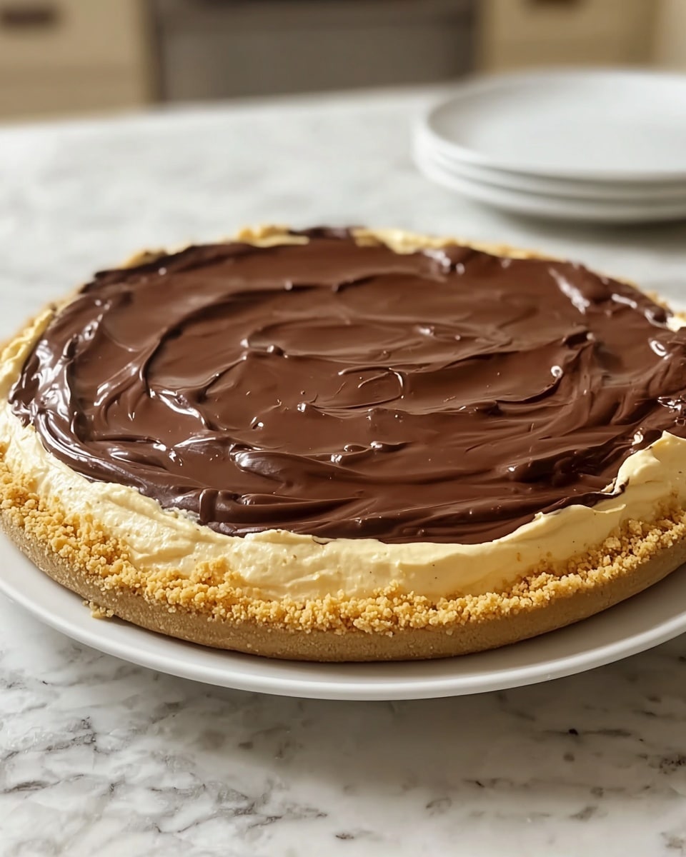 A three-layer dessert pie sits on a white plate over a white marbled surface. The bottom layer is a crumbly, golden-brown crust made from crushed cookies or graham crackers. The middle layer is a thick, creamy light beige filling with a smooth but slightly fluffy texture, rising slightly above the crust. The top layer is a glossy, dark chocolate ganache spread evenly across the surface, with small swirls and a slightly wavy pattern, creating a rich contrast with the lighter middle layer. The edges of the chocolate slightly overlap the creamy filling along the pie's rim. Photo taken with an iphone --ar 4:5 --v 7
