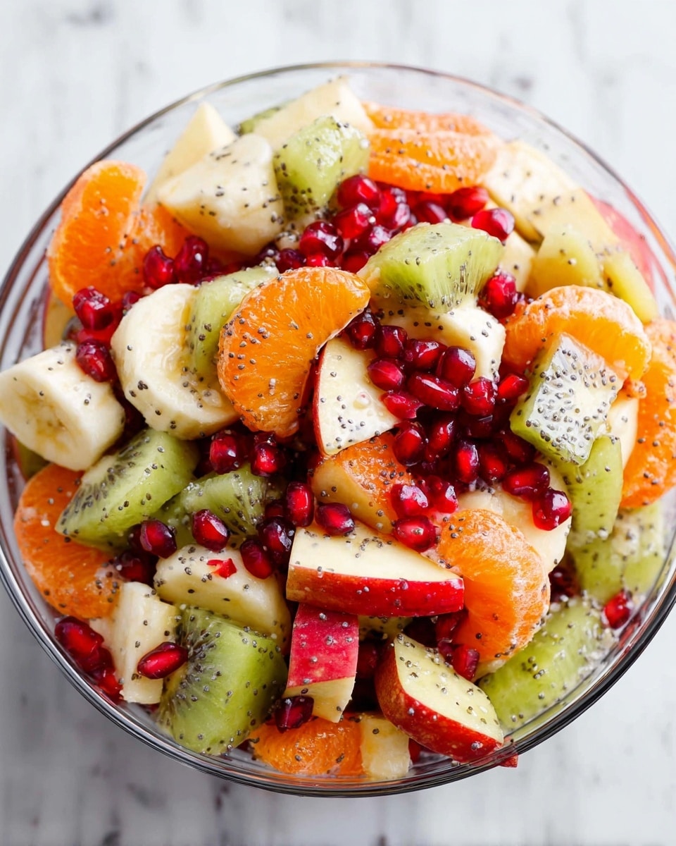 A close-up of a colorful fruit salad in a clear glass bowl placed on a white marbled surface. The salad has several layers of fresh fruit pieces: bright orange slices of mandarin, vibrant green slices of kiwi with tiny black seeds, thick chunks of red and white apple, pale yellow banana slices sprinkled with poppy seeds, and scattered shiny red pomegranate seeds. The fruit pieces mix together, showing a contrast of soft, juicy textures and bright, fresh colors. photo taken with an iphone --ar 4:5 --v 7