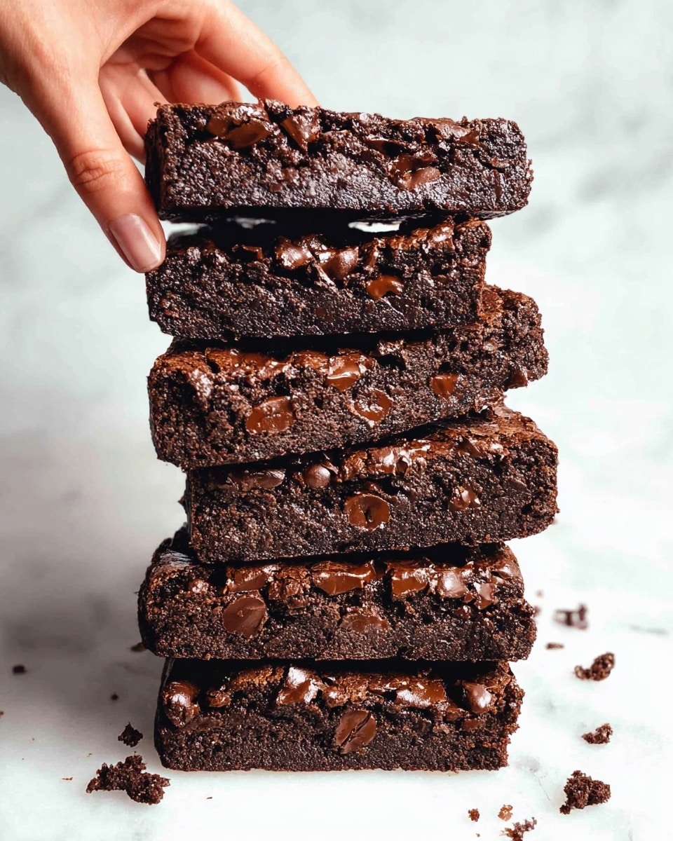 A stack of seven thick, rectangular chocolate brownies with a rich dark brown color and a slightly cracked surface is shown. Each brownie is studded with many small, melted chocolate chips that add texture and shine. The brownies are stacked unevenly, slightly tilted against each other, with some crumbs scattered around on a white marbled surface. A woman’s hand is pinching the edge of the bottom brownie, adding a sense of scale and interaction. The scene is brightly lit, highlighting the moist, fudgy texture and glossy chocolate chips. Photo taken with an iphone --ar 4:5 --v 7
